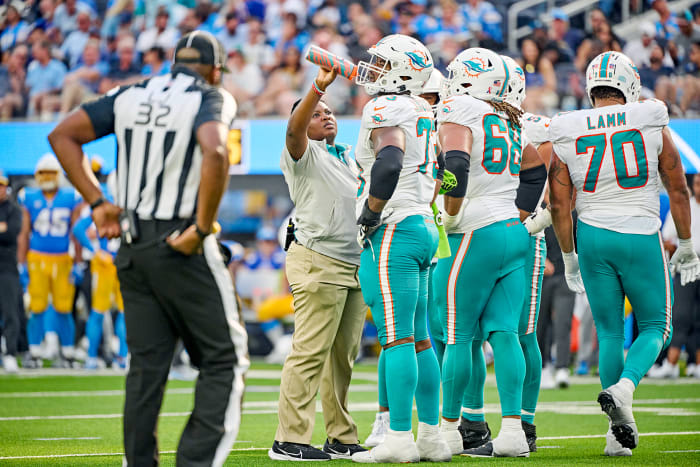 Dolphins assistant athletic trainer Jasmin Grimes runs onto the field with water during a game.